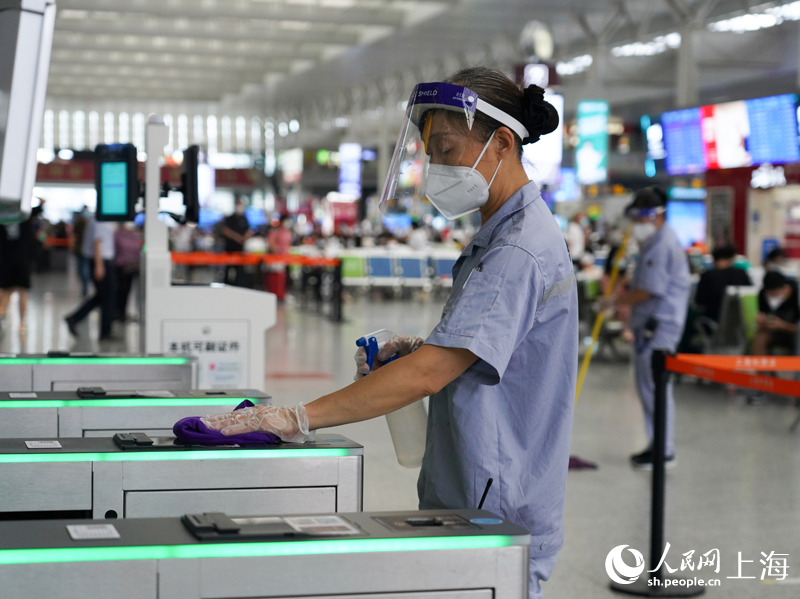 保潔員在上海虹橋火車站對進站閘機進行擦抹消毒作業。