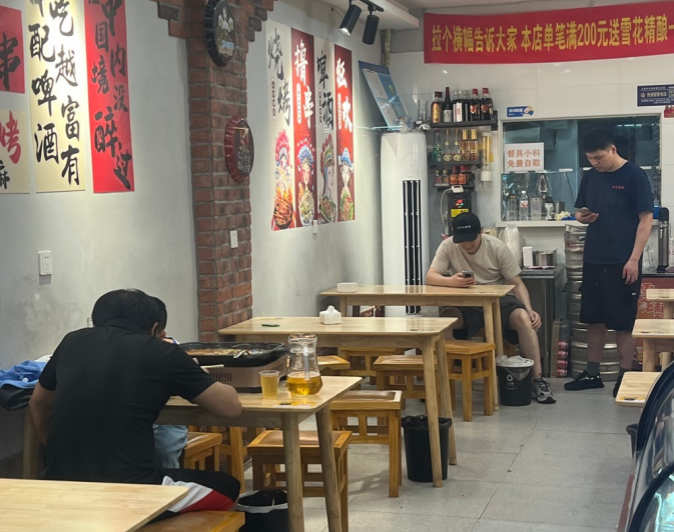 一家店面，兩班人馬：上海社區里的“拼店”生存術    這家名為“光頭大排檔”的小店藏著上海社區商業的一個獨特樣本：一個店面，兩組互不相識的經營者，兩套完全不同的經營業態，在24小時的循環中默契地交替登場。    燒烤的煙火取代雞公煲的香氣，陌生的兩組經營者交替接手這個小小的空間。雙方之前互不相識，卻在同一屋檐下形成了奇妙的共生關系。這種“時空共享”的商業模式，正在上海許多社區悄然興起，成為小微商戶應對高租金的一種生存智慧。
