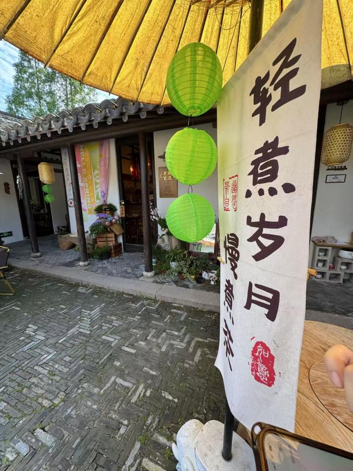 院內的油紙傘下，“輕煮歲月慢煮茶”七個字好似節拍器一般放慢了來客的步伐。人民網記者 龔莎攝
