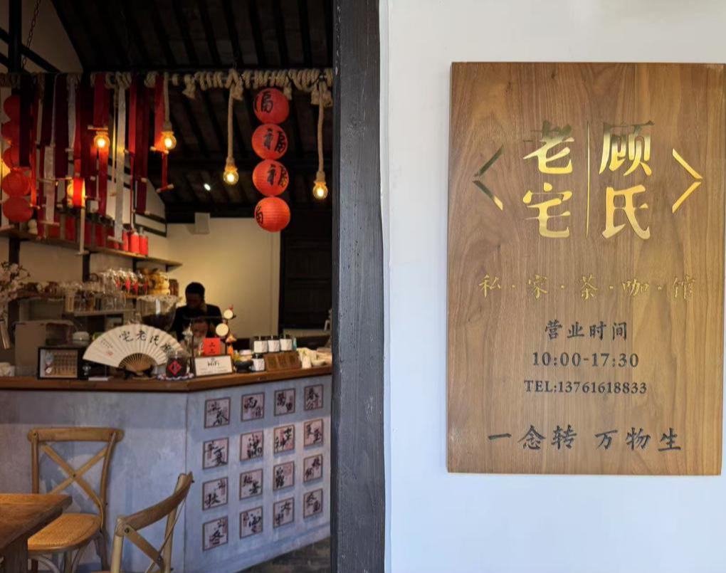 百年老宅里，茶咖香與煙火氣一同“醒來”    江南雨意裊裊。浦東新區周浦鎮棋桿村深處，一盞暖黃的燈籠亮起，光暈漫過顧氏老宅深褐色的木梁。曾經空曠、沉寂的老宅里，如今茶香升騰，人聲細碎。    顧家第十六代后人顧心瑤正擦拭著一張老方桌?！叭ツ昴甑走M來布置時，”她抬眼環顧，“老宅暮氣沉沉，空氣不流通，一股霉味?！比缃?，這座百年的絞圈房“活”過來了。